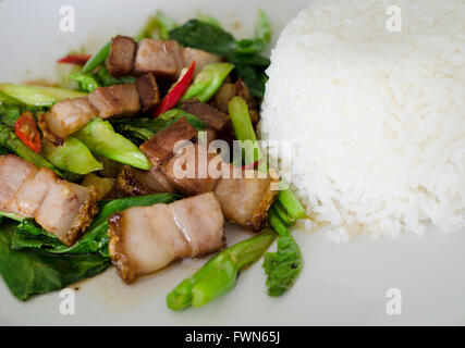 Kurz angebratenes Grünkohl mit knusprigem Schweinefleisch und Reis Stockfoto