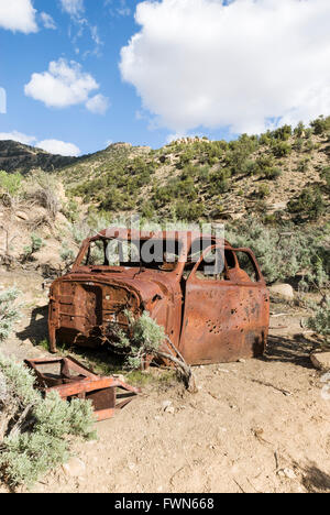 Ein rostiges Autowrack, gespickt mit Einschusslöchern liegt Rosten in der Nähe von Sego Geisterstadt, Utah, USA Stockfoto