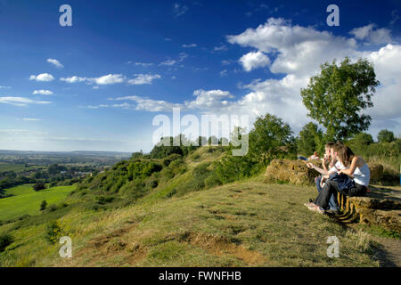 Junge Menschen genießen die Aussicht vom Schinken Hill Somerset England junges Mädchen Mädchen junge jungen Menschen essen Eis Eis sit Stockfoto