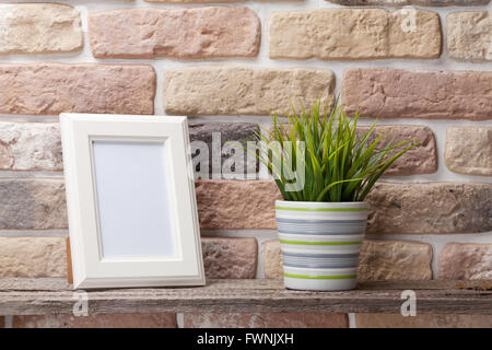 Leere Bilderrahmen und Pflanze Regal vor Backsteinmauer Stockfoto