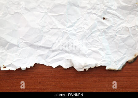 zerknitterte Papier mit verbrannten Ränder auf Holzbrett Stockfoto
