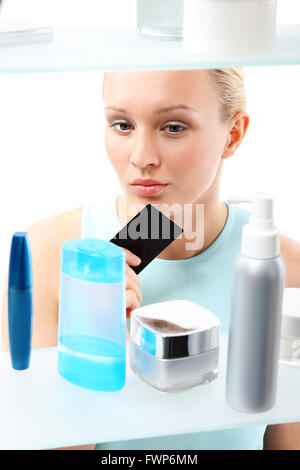 Eine Frau steht auf dem Client-Regal und wählt Kosmetik. Stockfoto