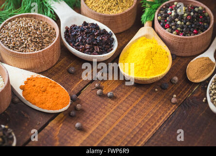 Schöne bunte Gewürze in hölzerne Löffel und Schüsseln auf einem alten hölzernen braun Tabelle. freier Platz für Ihren Text Stockfoto