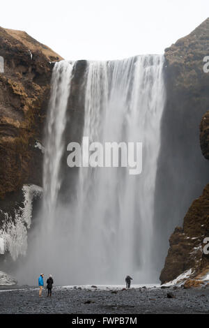 Touristen stehen vor Skogafoss Wasserfälle im winter Stockfoto