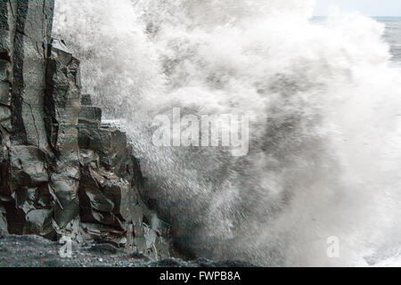 Nahaufnahme von Wellen, die gegen die Basaltsäulen am Reynisfjara Strand in der Nähe von Vik Stockfoto