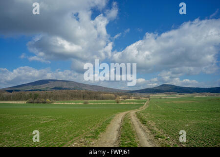 Mount Sleza und Mount Radunia mit sonnigen Frühlingshimmel, grünen Wiesen und unbefestigte Straße untere Schlesien Nieder Schlesien Stockfoto