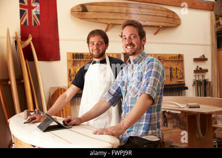 Tischler In Surfboard-Workshop mit Digital-Tablette Stockfoto