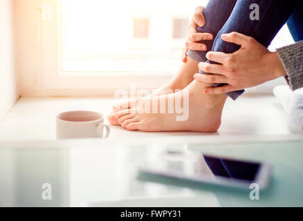Füße unkenntlich Frau sitzt auf der Fensterbank Stockfoto