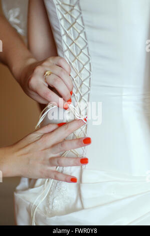 Brautjungfern helfen die Braut eine Hochzeitskleid tragen Stockfoto