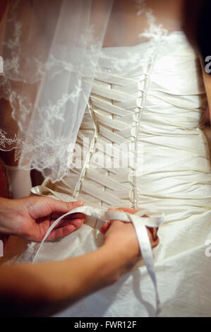 Brautjungfern helfen die Braut eine Hochzeitskleid tragen Stockfoto