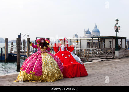 Zwei Damen in einem traditionellen venezianischen Karnevalskleid und Masken auf der Piazza San Marco. Stockfoto