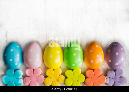 Bunte Ostereier und selbstgemachten Fondant überzogen Blume Cookies auf einem weißen Hintergrund Holz Stockfoto
