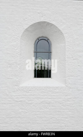 Gewölbte vergitterte Fenster in einer weißen Wand der Kirche Stockfoto