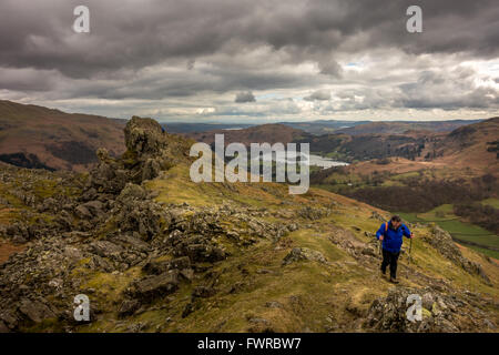Walker in der Ferne aufsteigend der Löwe und das Lamm auf Helm Crag, Lake District, Cumbria, UK Stockfoto