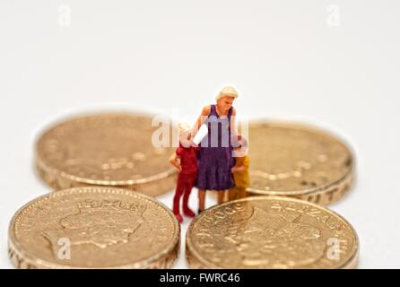 Eine Miniatur Figur Frau mit 2 Kindern steht zwischen einem Pfund-Münzen Stockfoto