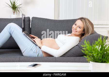 Schöne schwangere Frau zu Hause auf dem Sofa entspannen Stockfoto