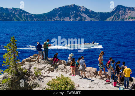 Touristen sehen, wie ein Ausflugsschiff Cleetwood Cove im Kratersee verlässt.  Crater Lake Nationalpark, Oregon Stockfoto