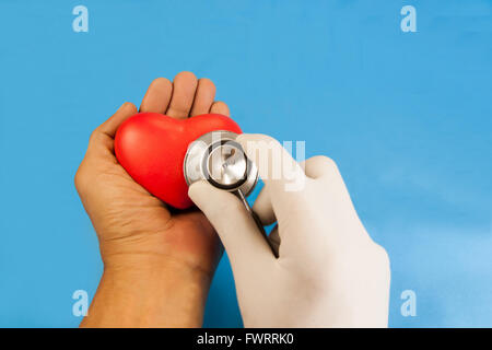 Herz-Check up vom Stethoskop. rotes Herz Keramik in der Hand auf blauen Hintergrund. Mit Schneidepfade. Stockfoto