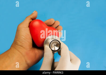 Herz-Check up vom Stethoskop. rotes Herz Keramik in der Hand auf blauen Hintergrund. Mit Schneidepfade. Stockfoto