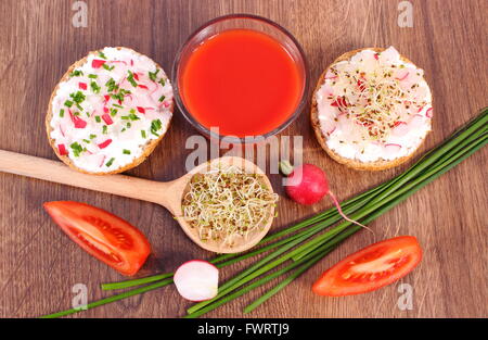 Frisch zubereitete vegetarische Sandwich mit Käse, Gemüse, Luzerne und Radieschen Sprossen, Glas Tomatensaft, gesunde Stockfoto