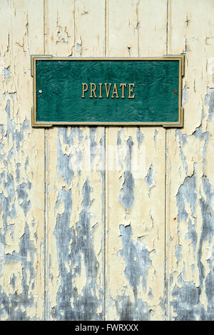 Private Zeichen auf einer alten bemalten gelben Holztür mit peeling Paint Textur Stockfoto