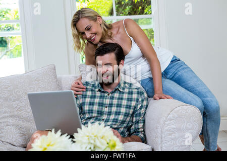 Frau auf Mann mit Laptop auf Sofa gelehnt Stockfoto