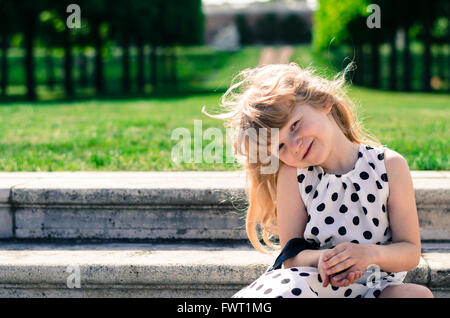 schöne blonde Mädchen sitzt auf der Treppe Stockfoto