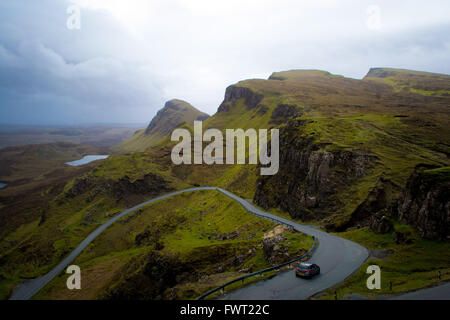 Ein Auto auf die kurvenreiche Straße führt durch die bergige Quiraing auf der Isle Of Skye, Schottland Stockfoto