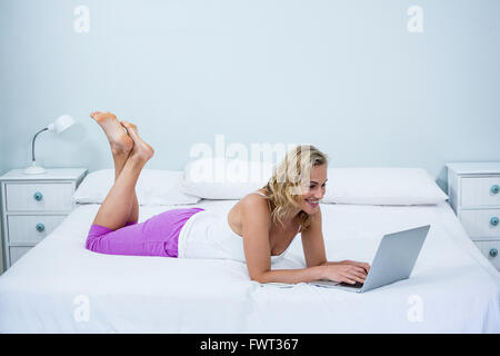 Seitenansicht der glückliche Frau mit Laptop auf dem Bett Stockfoto