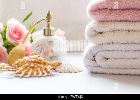 Bad-Gestaltung mit Parfüm-Flasche, gefaltete Handtücher und rosa Rosen Stockfoto