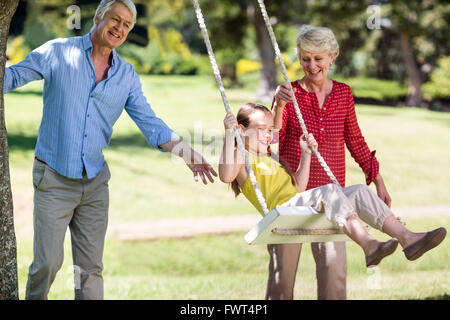 Die Großeltern ihre Enkelin Drücken auf Swing Stockfoto