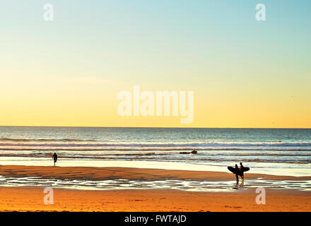 Paar Surfer am Ort zum Surfen am Meer Strand bei Sonnenuntergang Stockfoto