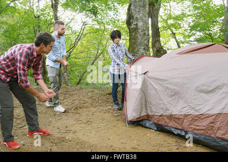 Multi-ethnischen Gruppe von Freunden, die ein Zelt auf einem Campingplatz aufstellen Stockfoto