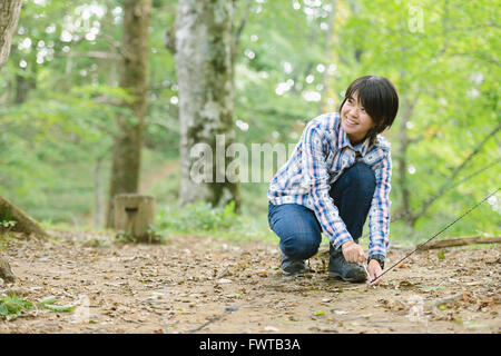 Junge japanische Frau, die ein Zelt auf einem Campingplatz aufstellen Stockfoto