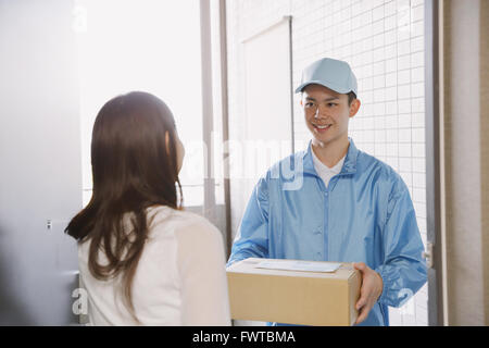 Junge Japanerin immer Paket von Lieferung Mann Stockfoto