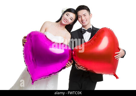 Glückliche Braut und Bräutigam hält herzförmige Luftballons Stockfoto