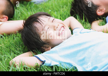 Japanische Kinder Verlegung auf Rasen in einem Stadtpark Stockfoto