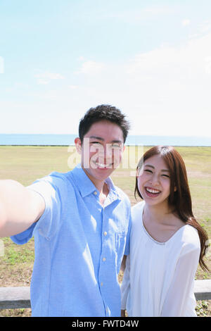 Junge japanische paar nehmen Selfie am Meer Stockfoto
