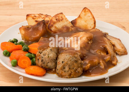 Ein gebratenes Huhn Abendessen mit Karotten und Erbsen, Salbei und Zwiebel Füllung Kugeln und Soße. Stockfoto