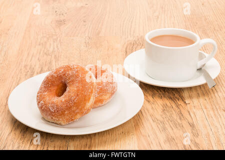 Zwei Zucker beschichtete Donuts auf einen Teller legen und ein heißes Getränk Stockfoto