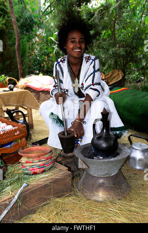 Eine junge äthiopische Frau Mahlen der Kaffeebohnen während einer traditionellen Kaffee-Zeremonie. Stockfoto