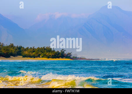 Wellen am Strand bei Sonnenaufgang in Baldwin Park West Maui Mountains im Hintergrund, Maui Stockfoto