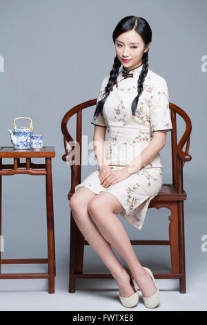 Junge schöne Frau im traditionellen Cheongsam mit Tee-set Stockfoto