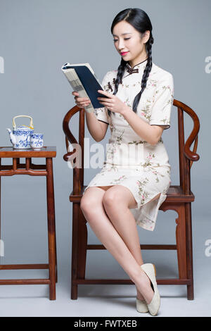 Junge schöne Frau im traditionellen Cheongsam Buch Stockfoto