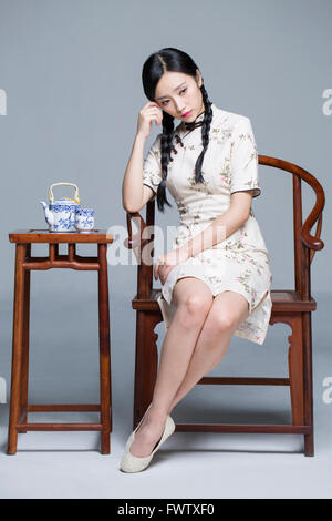 Junge schöne Frau im traditionellen Cheongsam mit Tee-set Stockfoto
