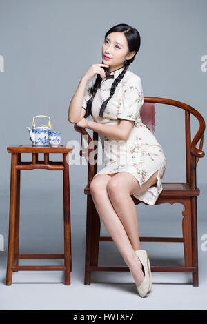 Junge schöne Frau im traditionellen Cheongsam mit Tee-set Stockfoto