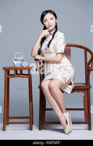 Junge schöne Frau im traditionellen Cheongsam mit Tee-set Stockfoto