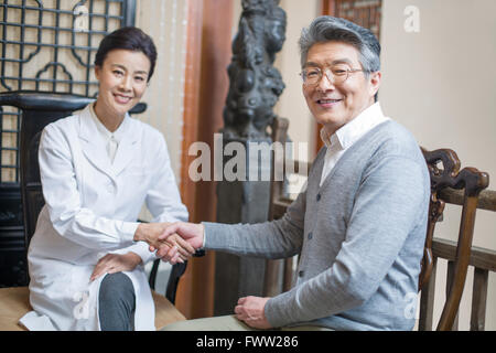 Chinesische Ärztin Händeschütteln mit Patienten Stockfoto