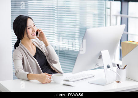 Junge Frau am Telefon im Büro Stockfoto