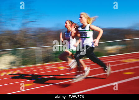 Pan Unschärfe Blick auf High School Mädchen Leichtathletik-Team läuft auf synthetische Oberfläche Outdoor-Strecke Stockfoto